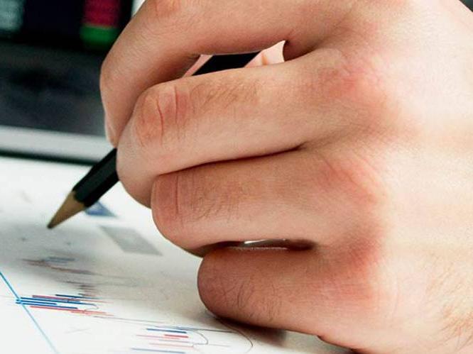 Student hovering over paper with pencil looking at graphs on paper