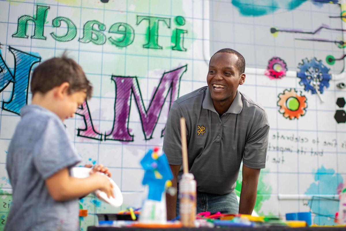 Man smiling at a child that is working on a project