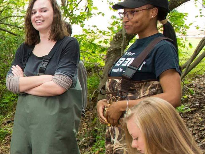 Students gathered around surrounded by trees and nature having a conversation