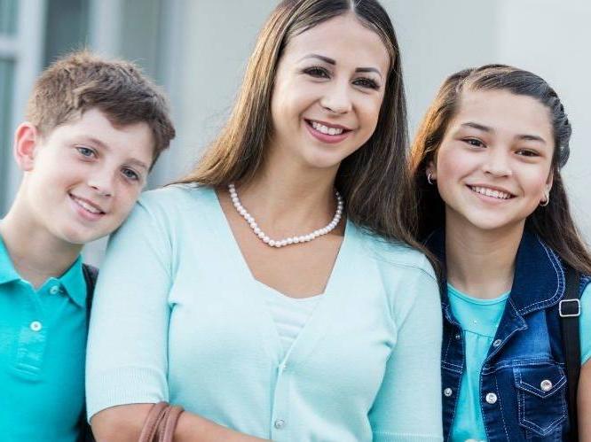 Woman and younger children standing together smiling for picture